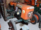 a small tractor in a garage with other farm equipment