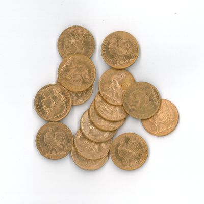 quelques pièces d'or posées sur une surface blanche, en petit nombre