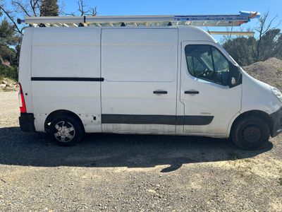une camionnette blanche garée sur un parking, avec une échelle sur le toit