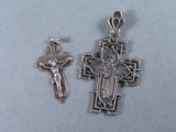 deux pendentifs en forme de croix en argent, avec un crucifix, posés sur une table