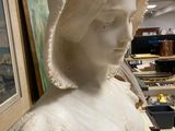 a statue of a woman with a bonnet on a table