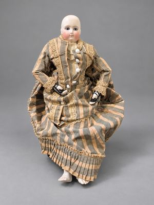 an antique doll of a woman in a striped dress and hat
