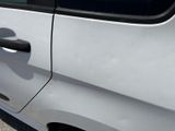 a small white car with a black handle on the side of the road