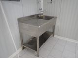 a stainless steel sink in the corner of a bathroom