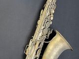 an old silver saxophone sitting on top of a black surface
