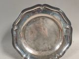 une assiette en argent posée sur une table, sur fond blanc