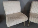 pair of cream colored chairs with gold legs in a room