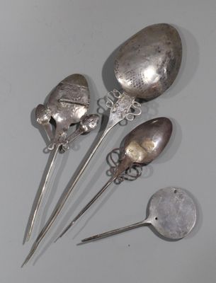 trois cuillères et deux cuillères en argent sur une surface blanche