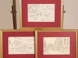 three framed drawings of a street scene in a red frame