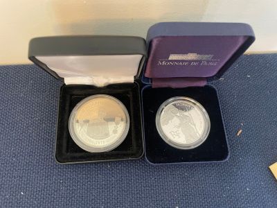 two silver and gold coins in a purple box on a blue carpet