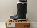 black and white rubber boots on top of a box on a white surface