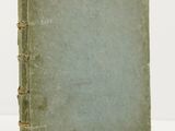 an old book sitting on top of a white table next to a white wall