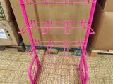 a pink metal rack with four shelves on top of it