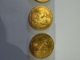 trois pièces d'or posées sur une table près d'un mur blanc
