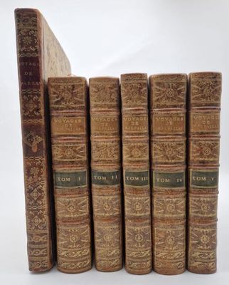 six vieux livres alignés sur une surface blanche