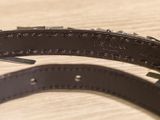 a black leather belt with rivets on a wooden table