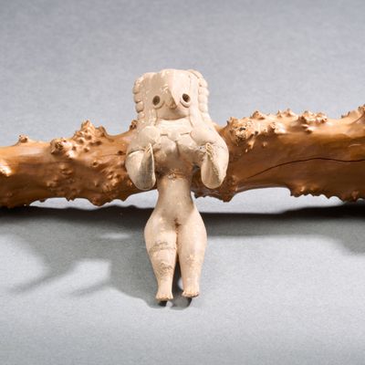 une petite figurine représentant une femme tenant une branche