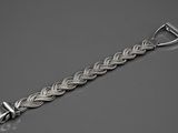 un gros plan d'un bracelet en argent posé sur une surface grise