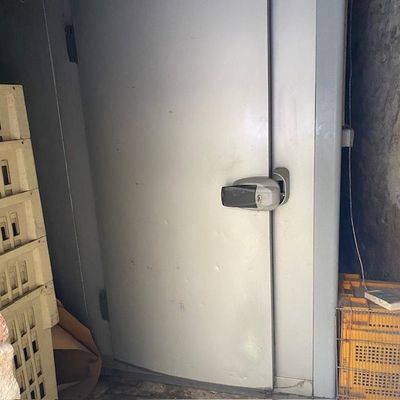 un réfrigérateur blanc dans un coin de la pièce, à côté de caisses