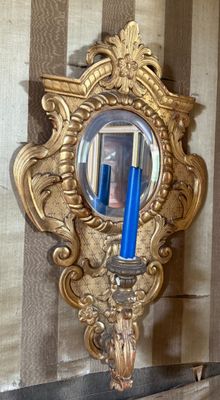 a gold mirror with a blue candle in it on the wall
