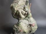 statue d'une femme assise sur un rocher, avec un oiseau sur le dos