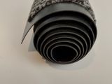 un rouleau de moquette noire et blanche posé sur une surface blanche