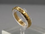 un gros plan d'une bague en or posée sur une surface transparente