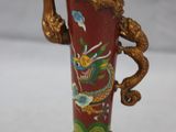 un vase rouge orné d'une poignée en forme de dragon doré