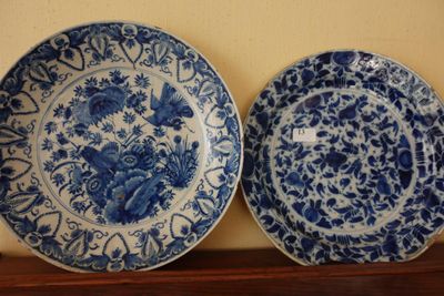 une paire d'assiettes bleues et blanches ornées de motifs floraux, posées sur une étagère