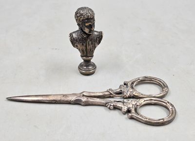 a pair of scissors sitting next to a bust of a man