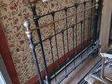a bed with a metal frame in a room with a wallpapered wall
