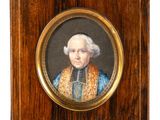une vieille photo représentant un homme vêtu d'un costume bleu et or, dans un cadre en bois