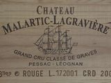 une caisse en bois sur laquelle est accrochée une pancarte indiquant « Château Malatric Lagravre »