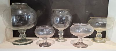 de nombreux verres et vases posés sur une étagère dans une pièce