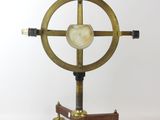 une horloge dorée et noire posée sur un socle, sur fond blanc
