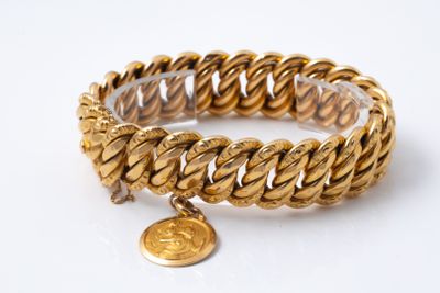 a close up of a gold bracelet with a coin on it