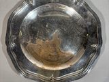 a silver plate on a wall with a bird on it
