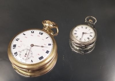 une montre de poche en or et une montre de poche en argent posées sur une table