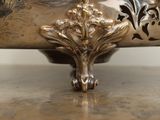 a silver bowl on a wooden table with a white wall in the background
