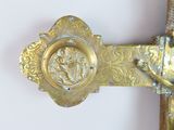a cross with a gold decoration on it against a white wall