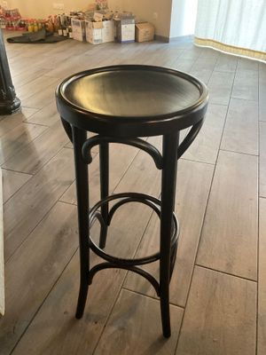 un tabouret noir posé sur le parquet d'un salon