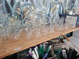 bottles and glasses on a shelf in front of a wallpapered wall