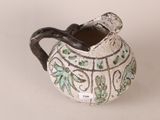 a white and green vase with a handle on it