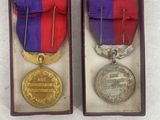 two medals are in a wooden box on a white surface