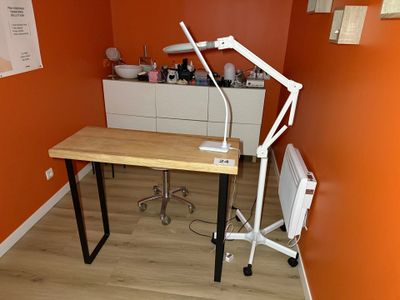 un bureau sur lequel est posée une lampe, dans un coin de la pièce