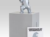 silver sculpture of a bear holding a baseball bat on top of a white box
