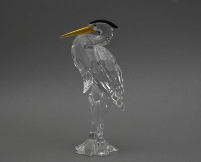 sculpture en verre transparent représentant un oiseau au bec jaune sur fond gris