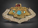 un gros plan d'une broche en or et en turquoise sur fond noir