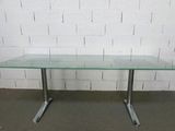 une table en verre avec des pieds en métal et un plateau en verre