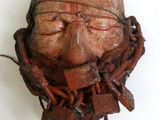 un visage sculpté dans un morceau de bois posé sur une surface blanche